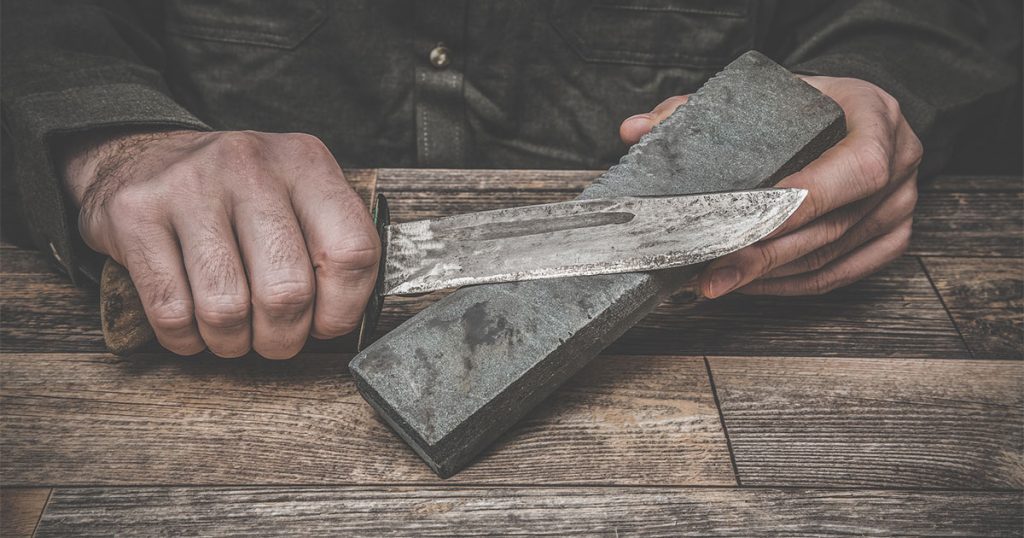 hands sharpening knives on stone