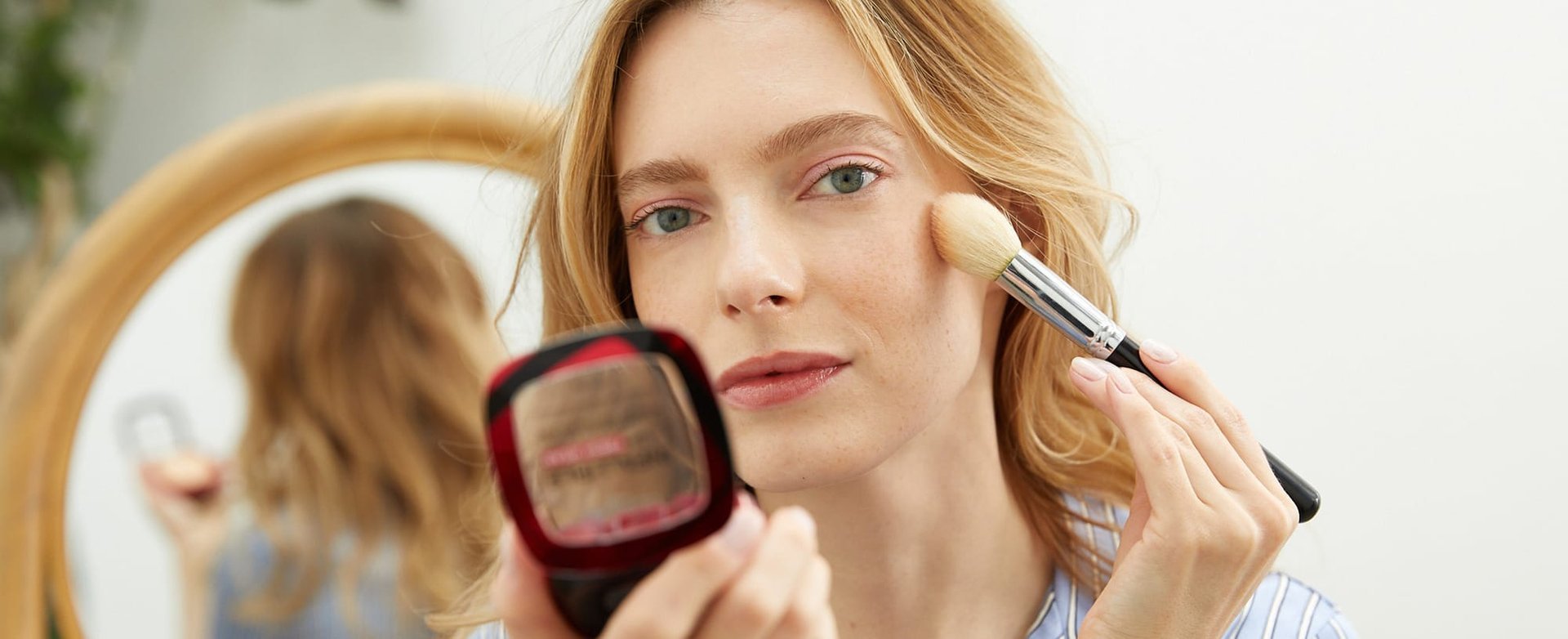 woman applying makeup in bright natural light