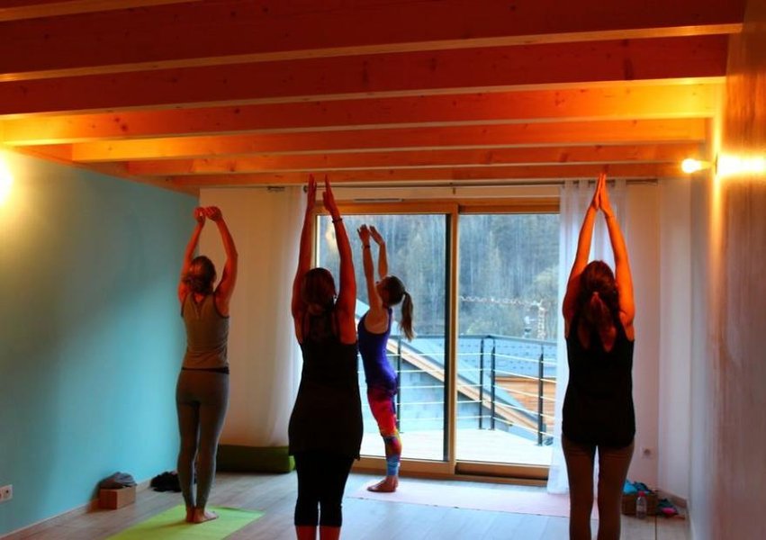 Persona realizando una postura de yoga avanzada al aire libre con montañas de fondo
