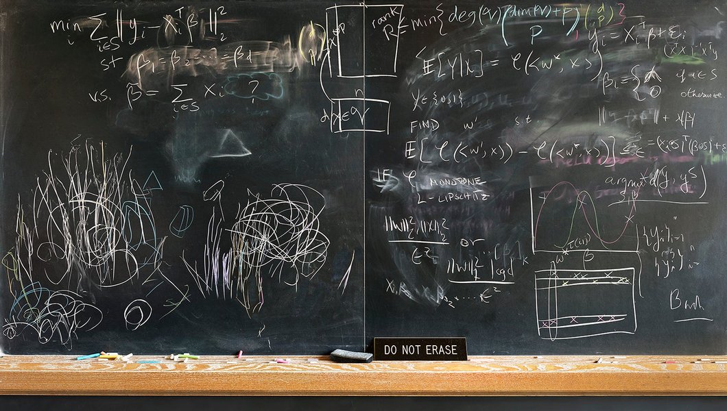 Person writing complex math equations on a large blackboard