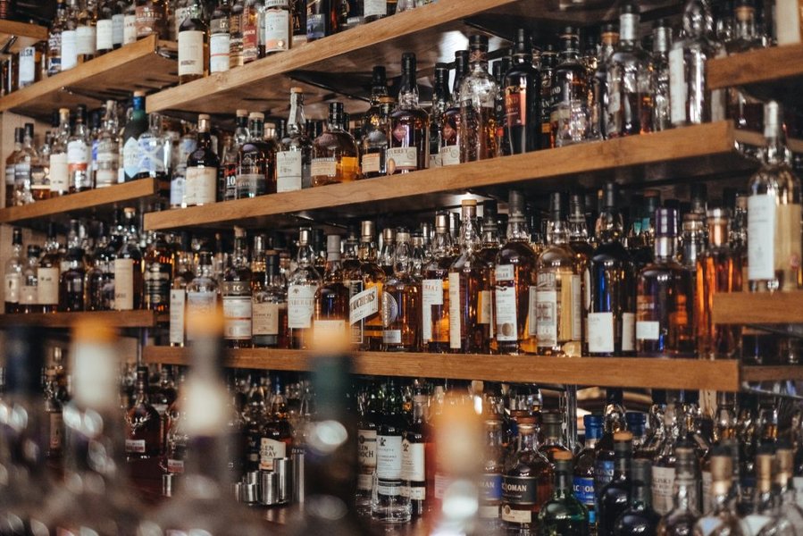 Estanterías llenas de diversas botellas de licor en una tienda bien iluminada
