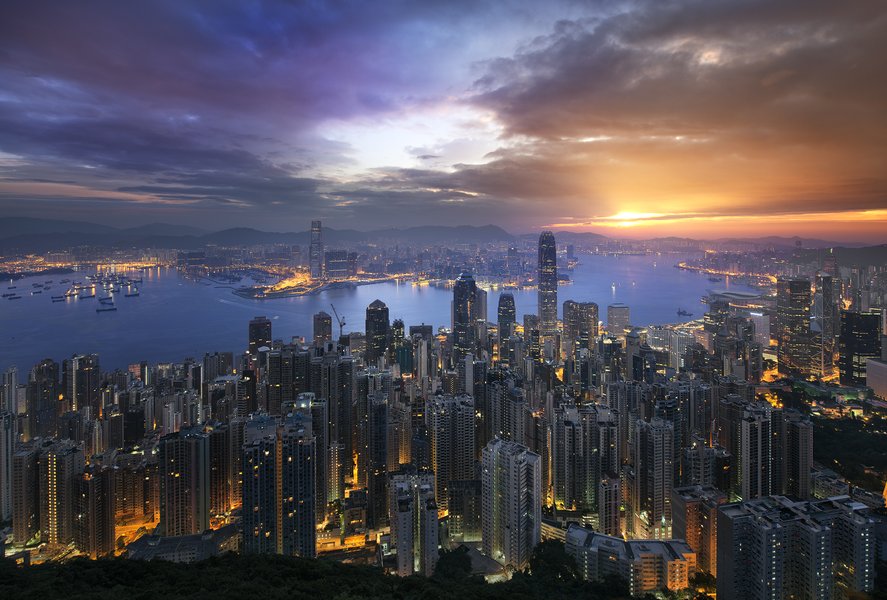 Densely packed skyscrapers forming the Hong Kong skyline at night, illuminated against the water
