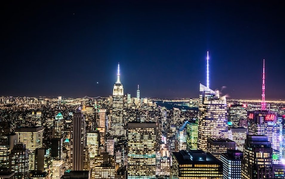 The Manhattan skyline at dusk, featuring illuminated skyscrapers and prominent landmarks like the Empire State Building