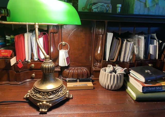vintage books on a wooden desk with paper and lamp