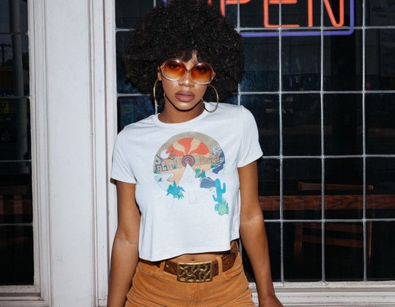 A woman models a flowy crop top with a psychedelic 70s-inspired design.