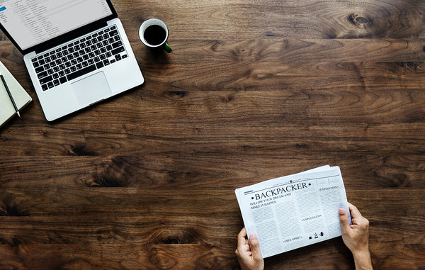desk with newspapers and laptop