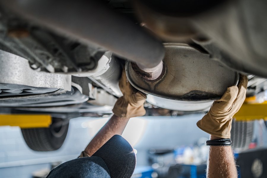 A mechanic performing a visual inspection of an exhaust system for potential leaks or damage.
