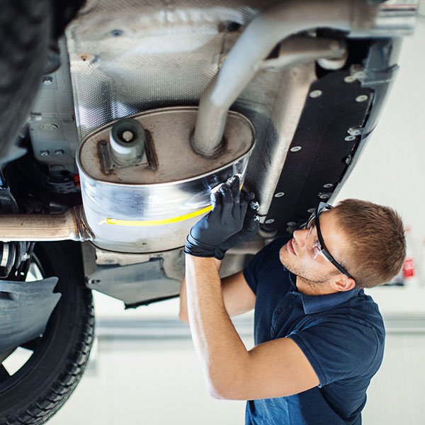 A technician inspecting an exhaust system for potential leaks or issues.
