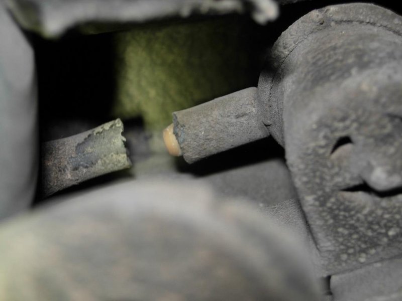 A close-up image showing a cracked and deteriorated rubber hose within a vehicle's engine bay.