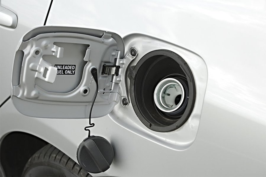A hand tightening a gas cap on a car, illustrating a common cause of P0455.