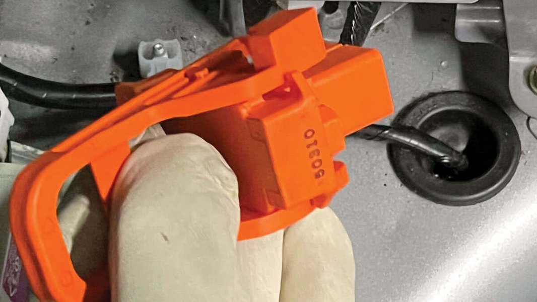 Technician using an insulation resistance tester on a hybrid vehicle's high-voltage system to check for ground faults.