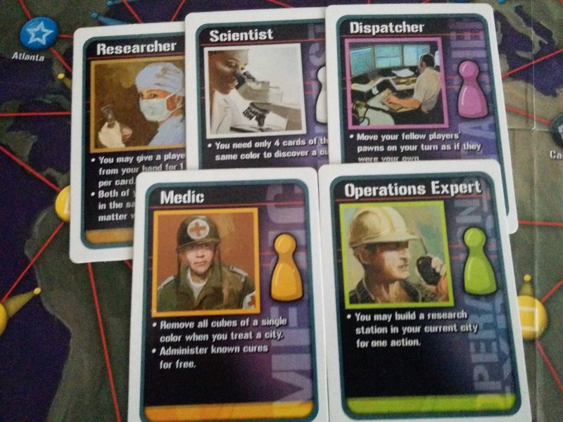 Peones de jugador y cartas de rol en Pandemic