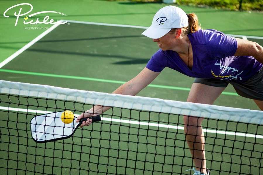 Player executing a dink shot at the net in pickleball