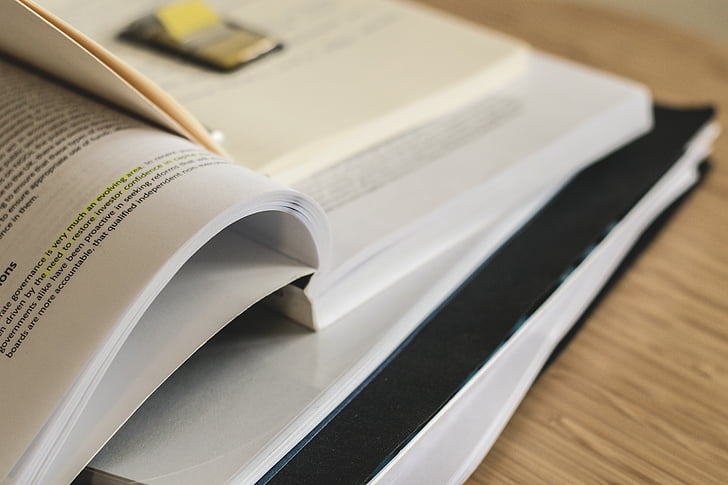 physical books open on a study desk with notes