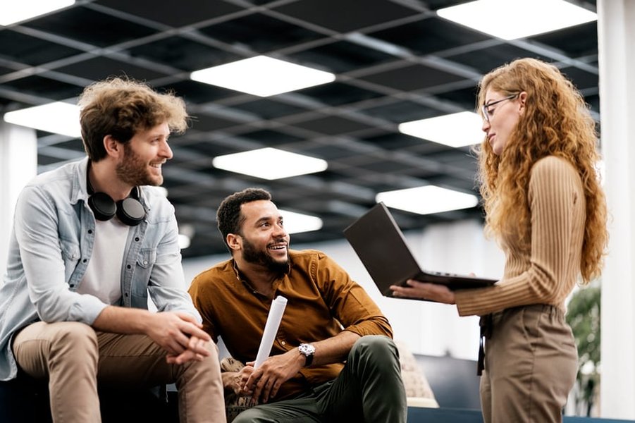 Coworkers chatting and having a conversation in an office setting.