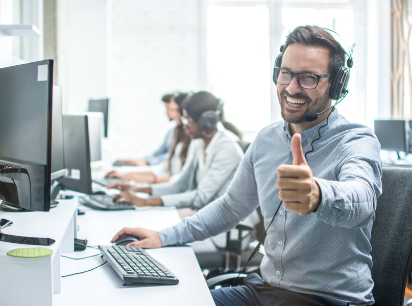 A group of diverse customer service agents working collaboratively in a call center environment.