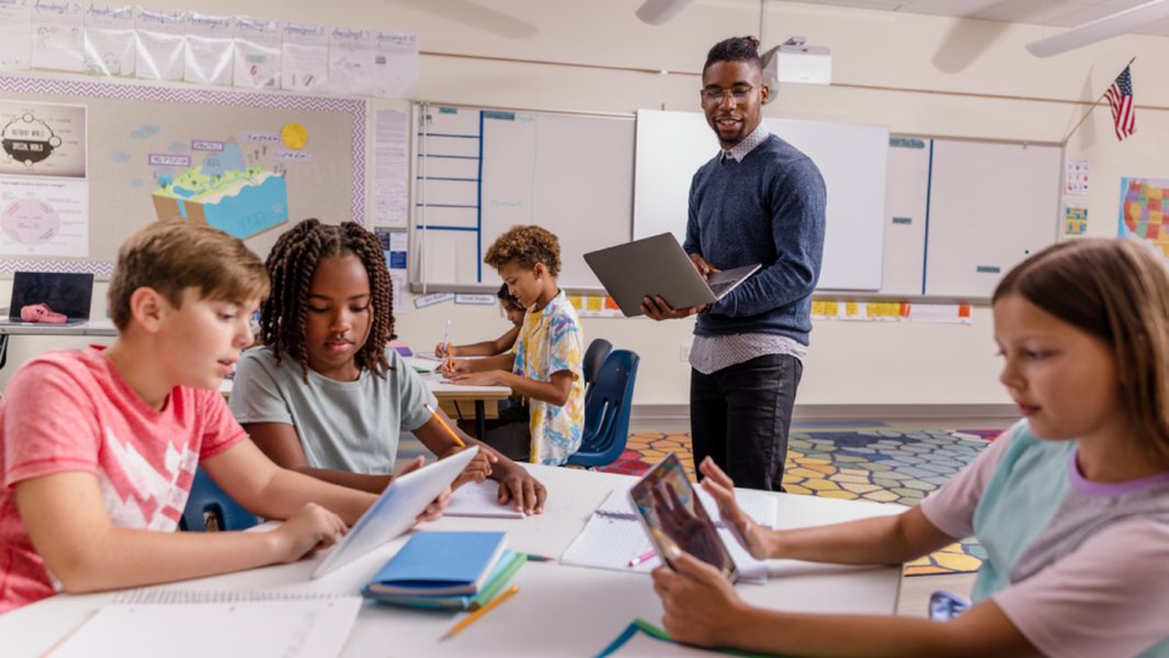 Teacher observing students as they read, indicating an educational setting.
