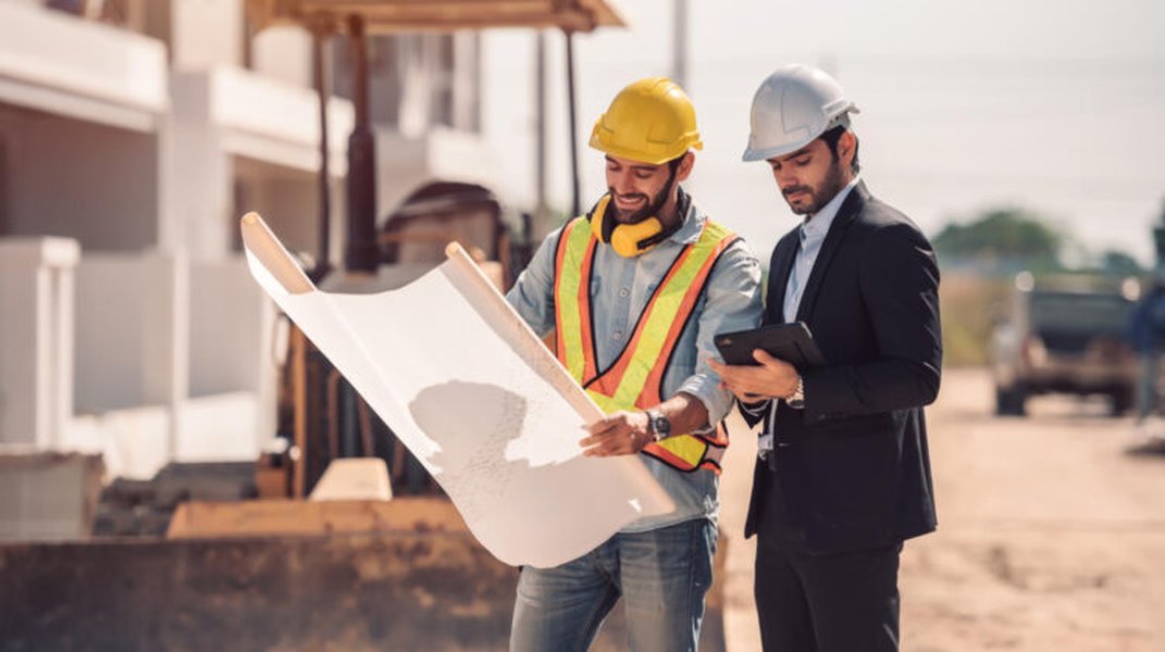 Ingenieros y trabajadores discutiendo planos en obra