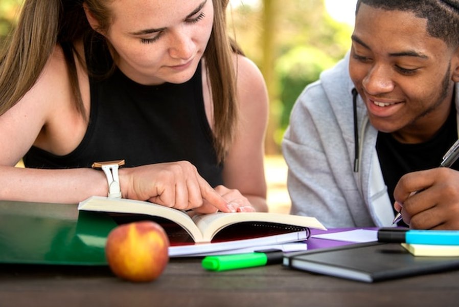 Estudiantes estudiando juntos al aire libre usando tecnología