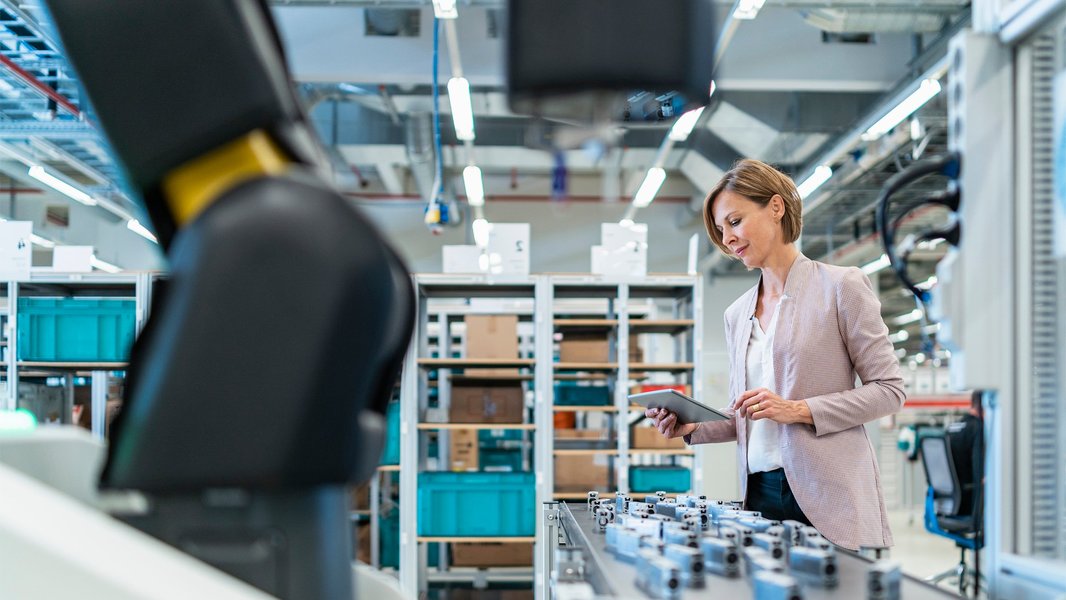 Une femme d'affaires examinant une tablette dans un environnement industriel