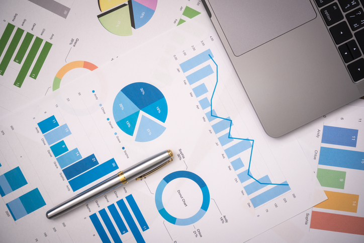 Financial documents, digital graphs, office desk