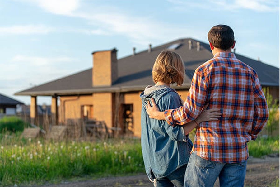 Happy couple with a 'Sold' sign in front of their new Texas home.
