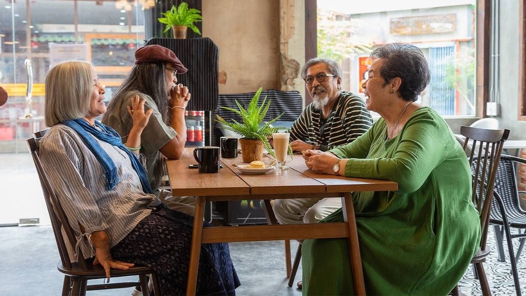 Diverse group of friends chatting and laughing around a table in a coffee shop