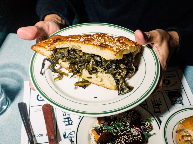 A vibrant, plant-based burger with fresh ingredients, served in a restaurant setting.