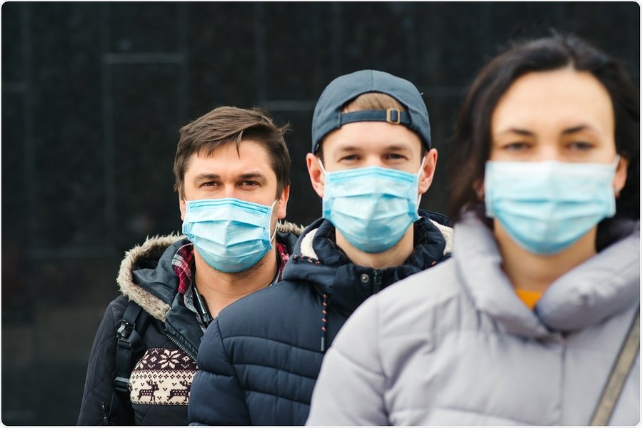 A person wearing a blue surgical mask, illustrating its use in a public setting.