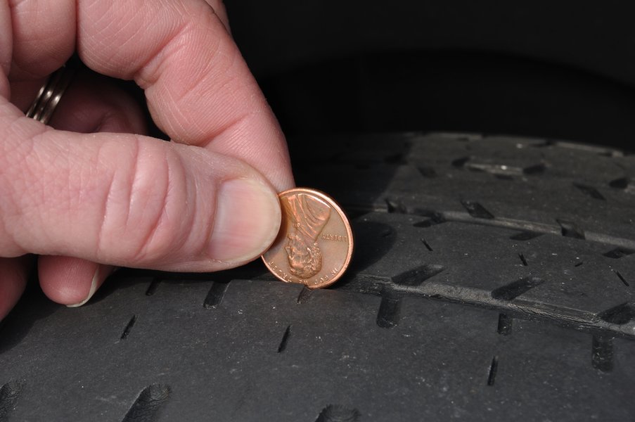 A visual demonstration of the classic penny test for assessing tire tread depth.