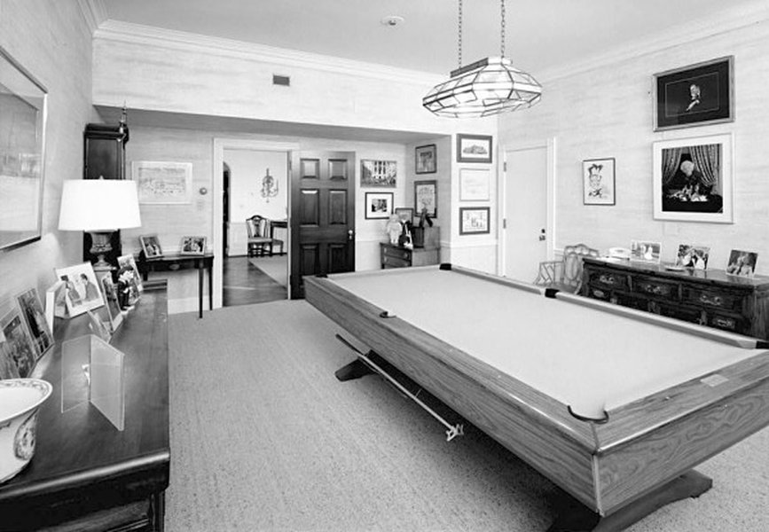 A photograph of the White House Game Room from 1992, featuring a pool table and a television, suggesting a recreational space.