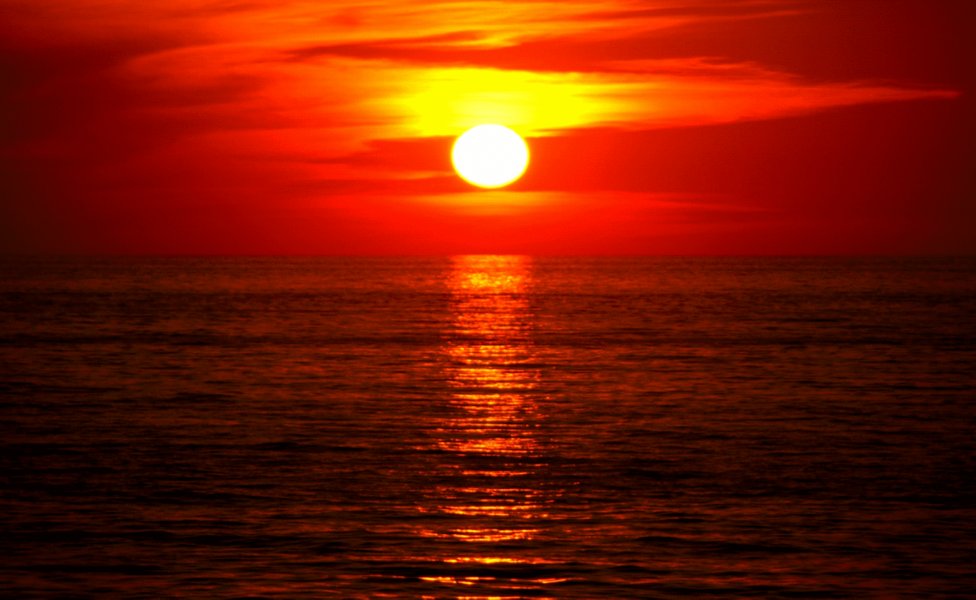 A vibrant red and orange sunset over a landscape.