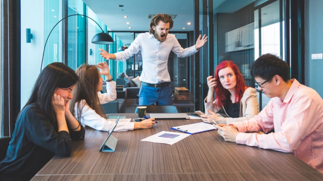 Two people in a workplace setting looking frustrated and in disagreement.