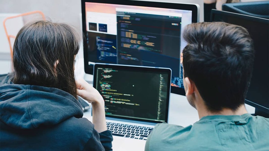 A programmer working on a computer with lines of code displayed on the screen.