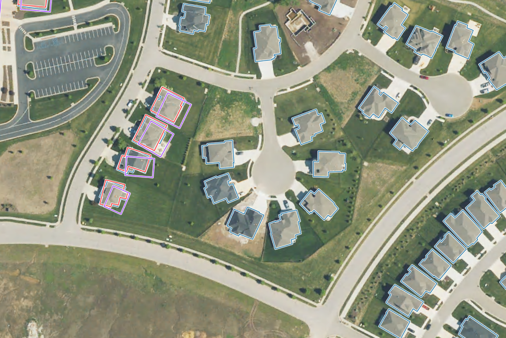 An image showing multiple building footprint datasets overlaid on aerial imagery