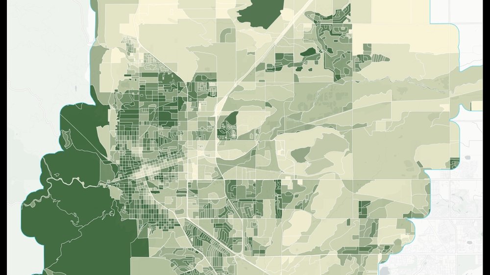 This TreePlotter choropleth map displays urban tree canopy density using a green-to-cream gradient overlaid with white street lines. The western edge and established residential street grids show the densest tree cover (dark green).