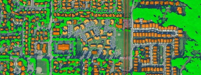 Aerial GIS map displaying suburban blocks, with individual buildings highlighted in orange outlines and tree canopy marked in bright lime green. A central multi-lane road divides residential housing grids on the left from large.