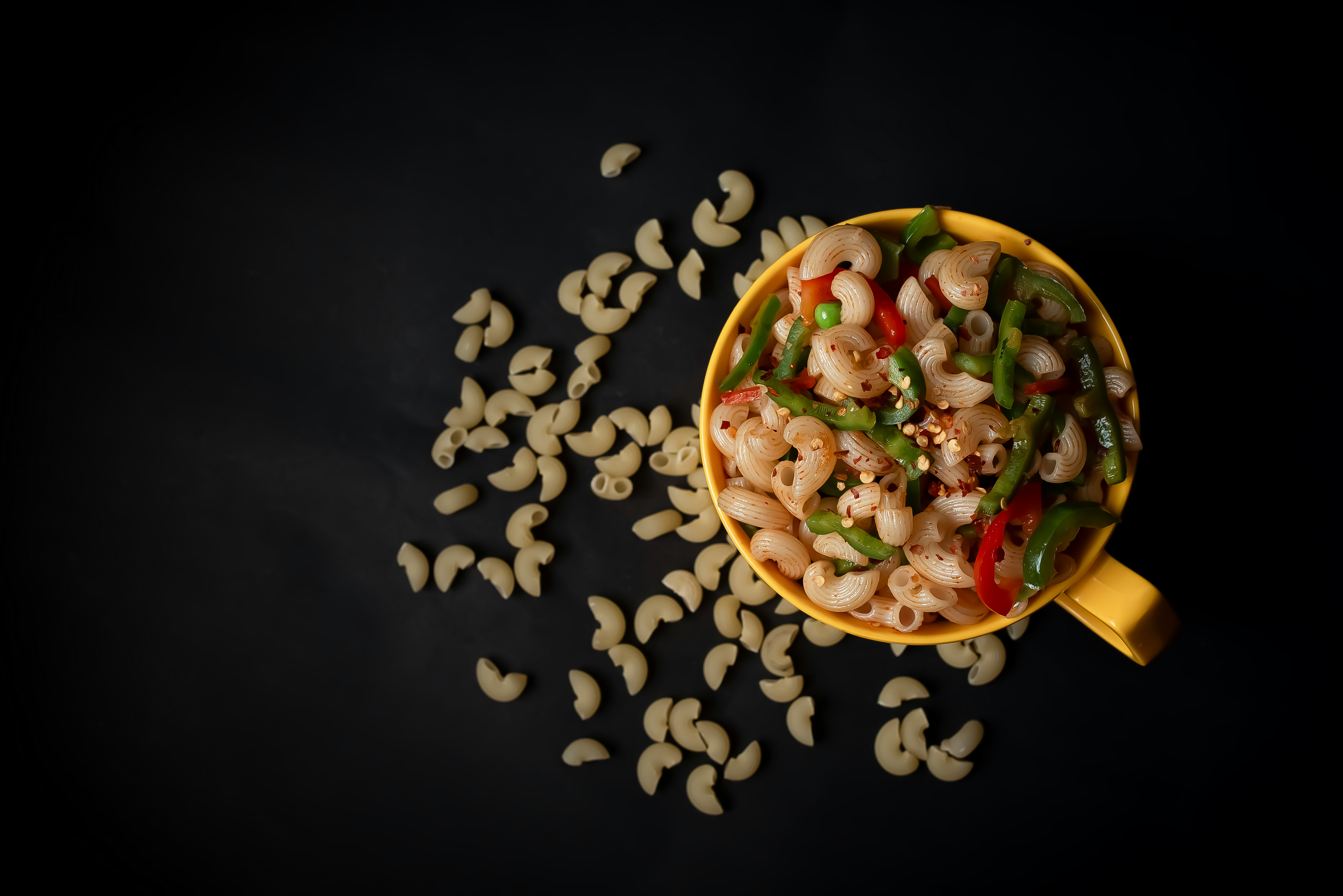 a yellow bowl filled with pasta and vegetables