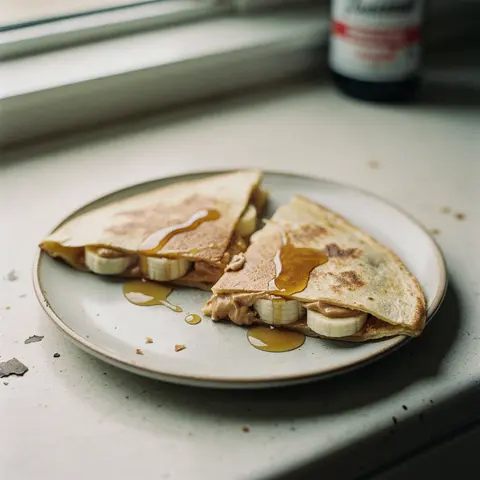 Folded corn tortilla quesadillas filled with banana and peanut butter, drizzled with maple syrup