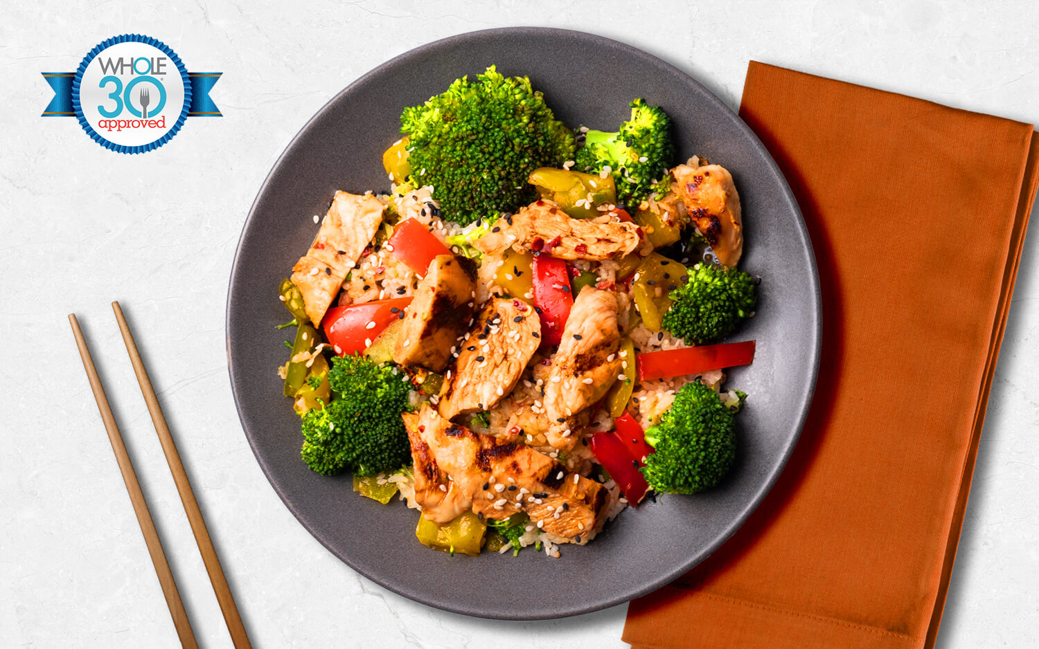 Chicken stir fry with cauliflower rice, teriyaki glaze, roasted bell peppers, broccoli, and topped with sesame seeds. 
