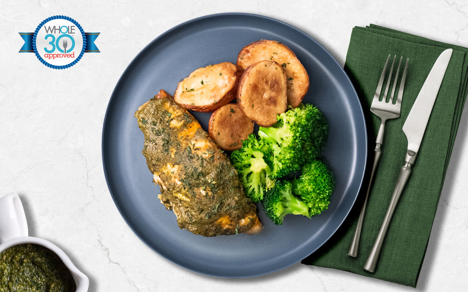 Salmon topped with pesto sauce, served with red skin potatoes and broccoli