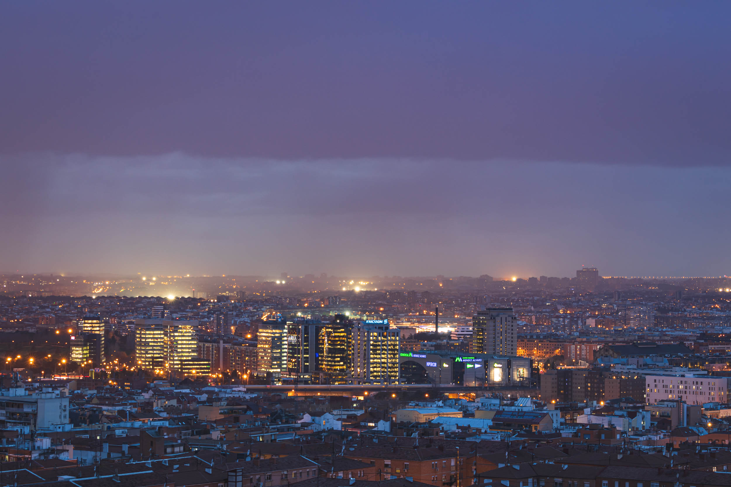 Rain pours on another area of the city while the sun sets.