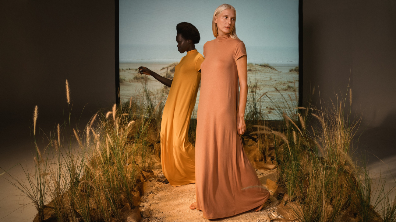Two women wearing floor-length modal dresses in earth tones.