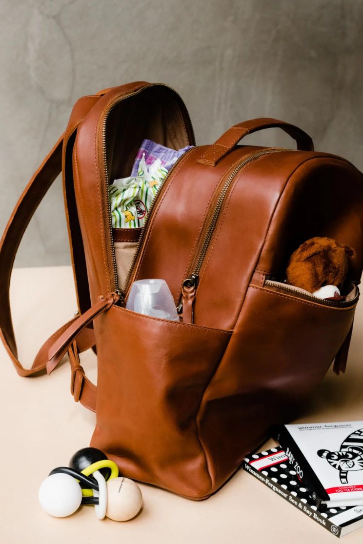 an alem backpack from able opened in the back pocket to reveal a number of baby items.