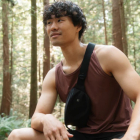 Man in forest wearing TenTree clothes: a red singlet and black fanny pack