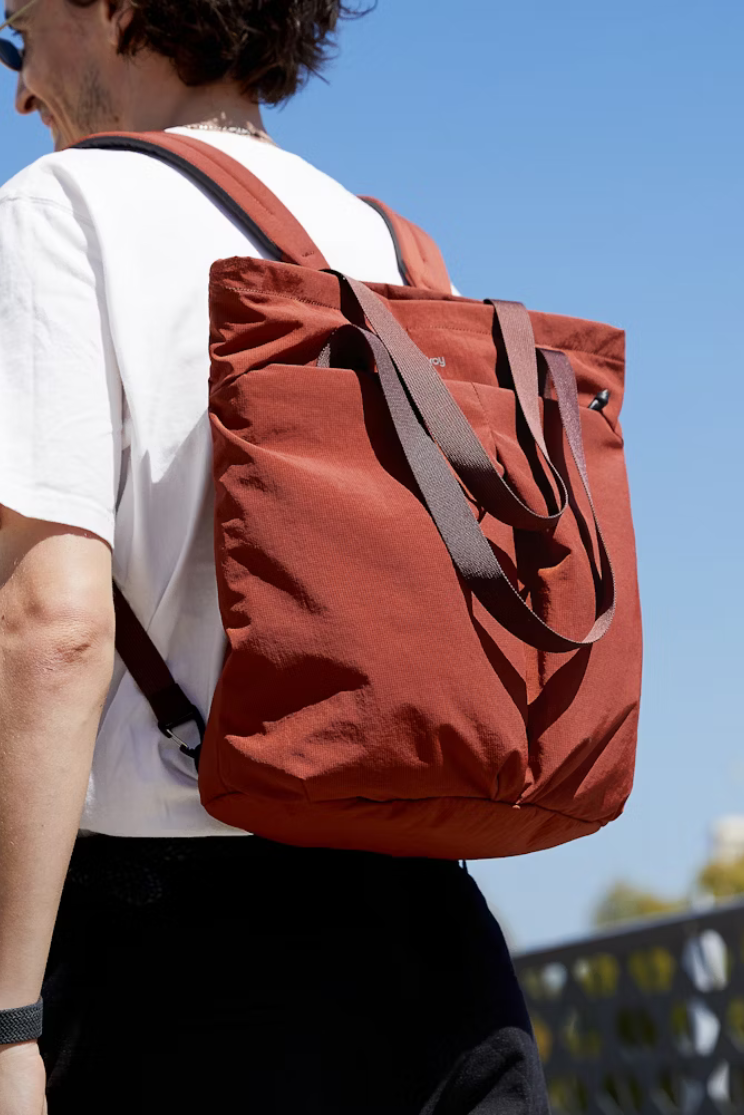 a person in a white shirt models the bellroy lite totepack in clay