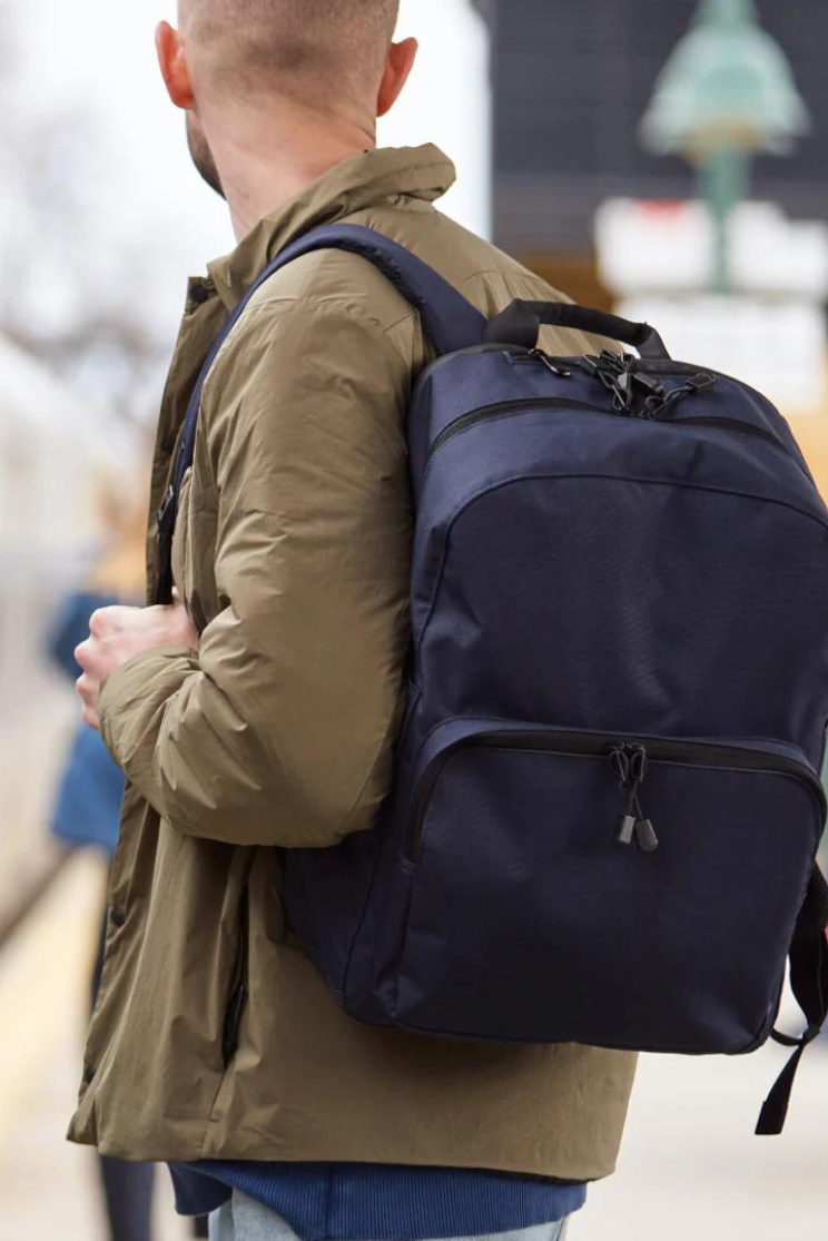 a person in a khaki coat models a blue hanover deluxe 2 backpack