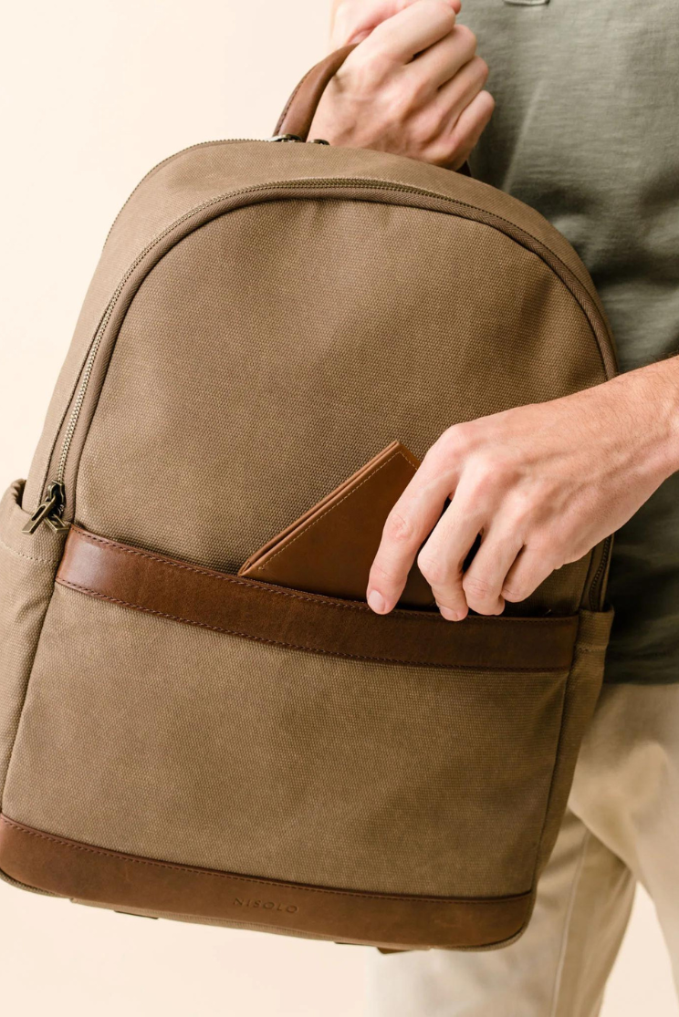 a close up shot of the alex commuter bag in beige and brown with a hand sliding a wallet into the front pocket