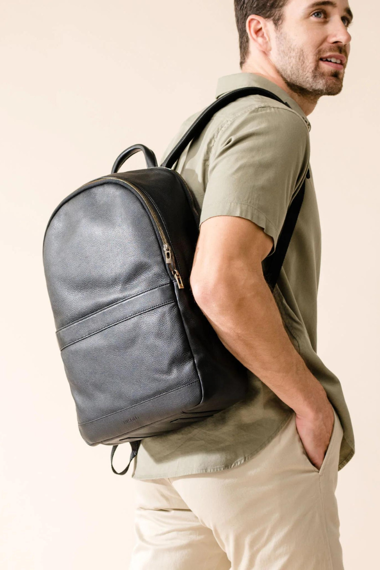 a person models the alex commuter bag in black from the opposite side as the first image.