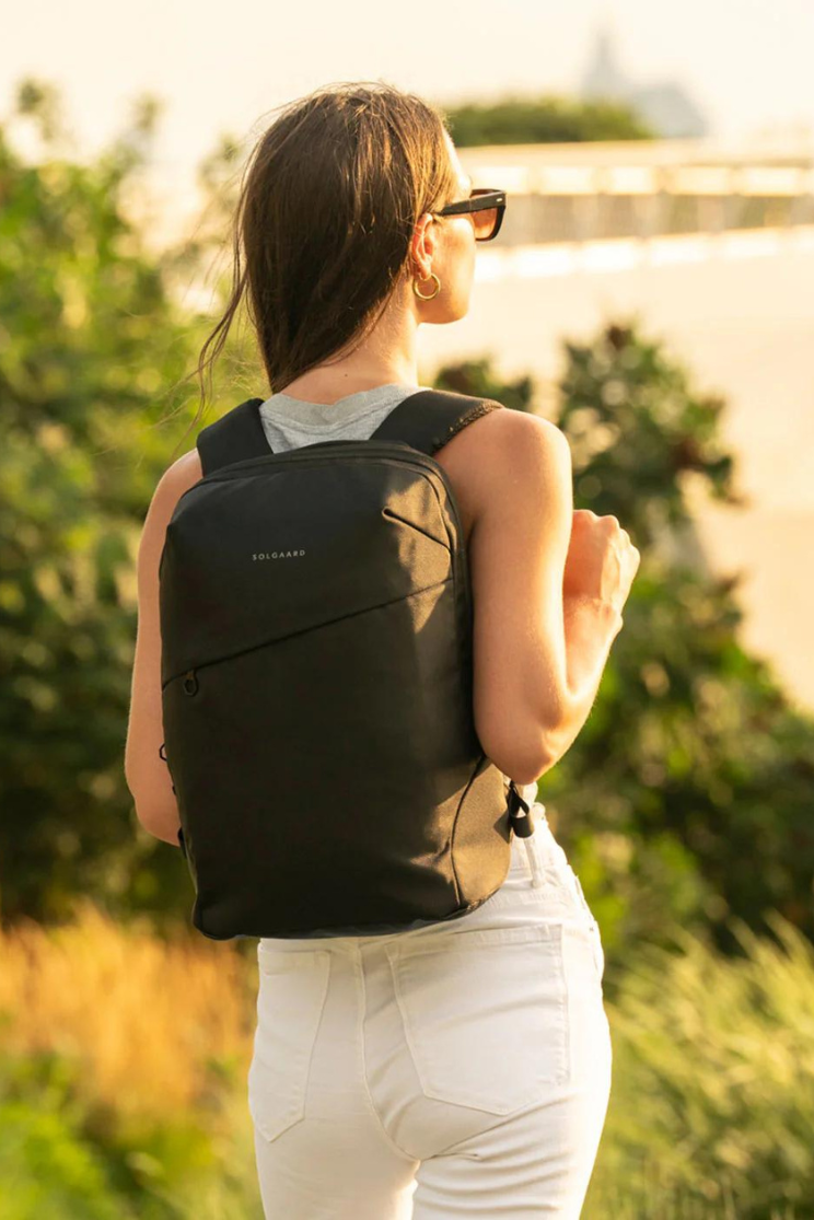 a person models a black artemis backpack, which has a flat back with a minimalist back pocket